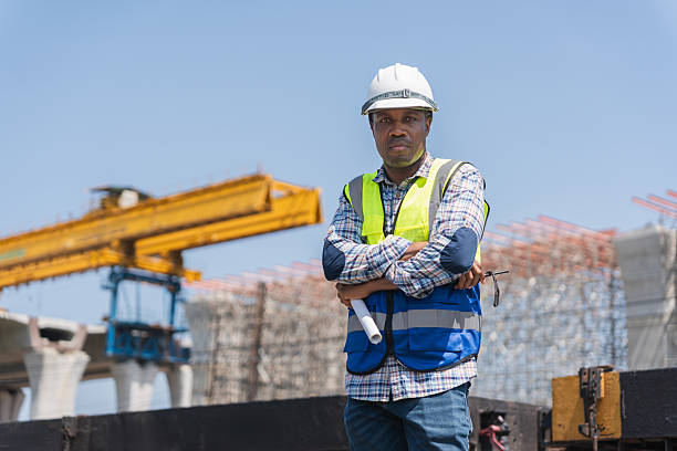 istock African American Engineer or Construction Worker on Site, Male Construction Manager with Hard Hat and Vest, Portrait of a Man in Safety Gear with Arms Crossed on Train Tracks 2220235803