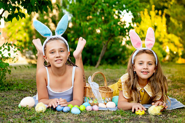 istock Easter, children play with Easter eggs in bunny ears on the green lawn. Easter tradition. Children with a basket full of colorful eggs 2220237874