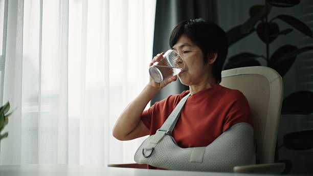 istock Mature woman with arm cast drinking water. 2220241330