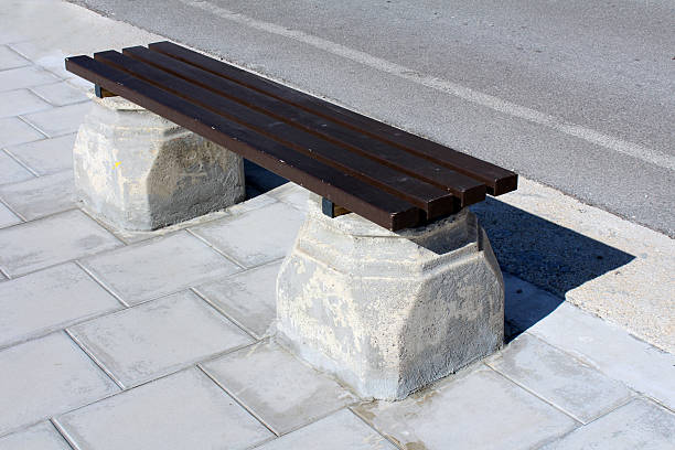 istock Concrete park bench with wooden slats on paved sidewalk 2220241914