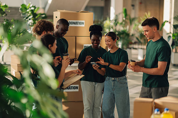 istock Volunteers using smartphone and organizing donations in cardboard boxes 2220243064