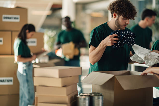 istock Volunteers sorting clothes and food donations in cardboard boxes 2220243217