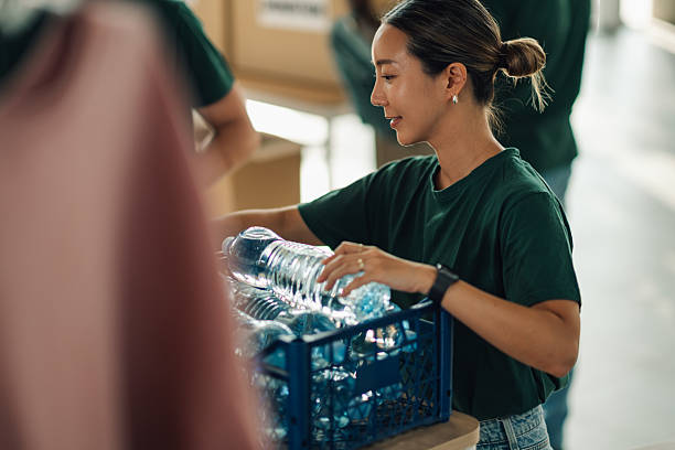 istock Volunteer organizing plastic bottles for recycling in community center 2220243232