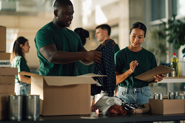 istock Volunteers sorting clothes and food in cardboard boxes for donation 2220243247