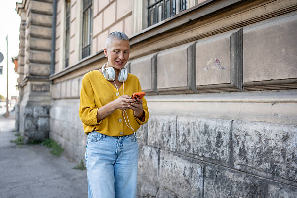 istock Woman Smiling While Using Smartphone Outdoors and Wearing Stylish Casual Outfit 2220243478