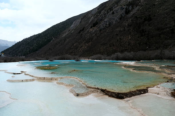 View of the Multi-Colored Pond, surrounded by the snow mountain in Huanglong, a World Heritage Site by UNESCO in 1992 because of its outstanding travertine formations, waterfalls and limestone formations as well as its travertine terraces and lakes rating among the three most outstanding examples in the world. Sichuan, China.