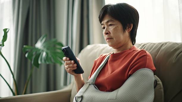 istock Mature woman with arm cast using smartphone. 2220245836