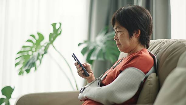 istock Mature woman with arm cast using smartphone. 2220245848