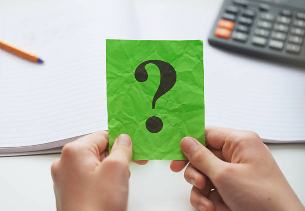 istock A student  holding a green paper note with a question mark on it in his hands over an open notebook and a calculator 2220246833