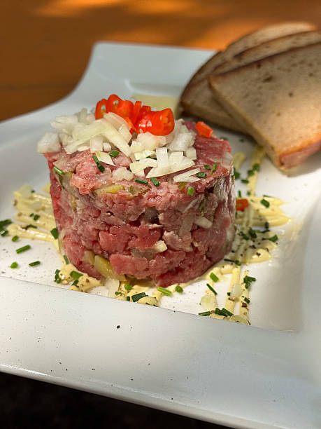 Raw beef tartare with egg and spices served on plate in restaurant