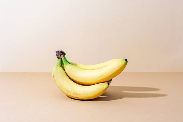 istock Fresh ripe bananas on beige background with sharp shadows. Closeup 2220252073