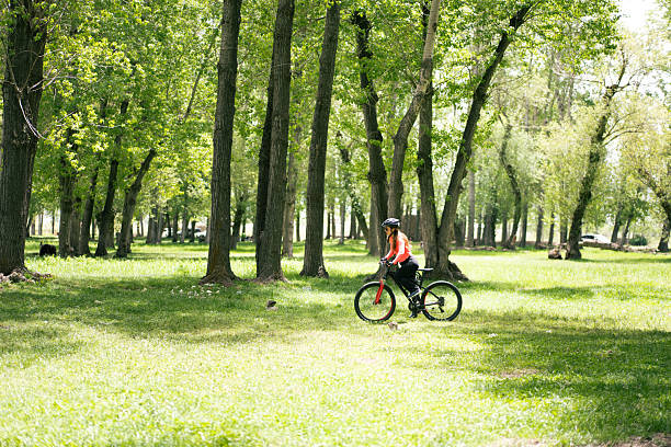 Young woman enjoying a leisurely bike ride through a peaceful park, surrounded by trees