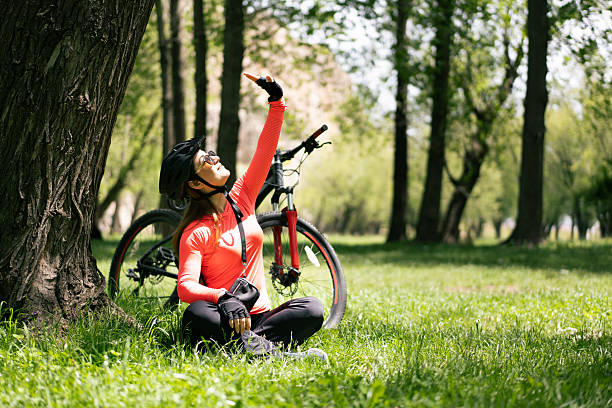 Young woman cyclist taking a break in the park, enjoying the sunlight