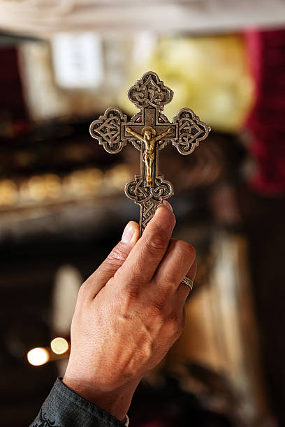 Hand of unrecognizable Orthodox priest holding the cross in church