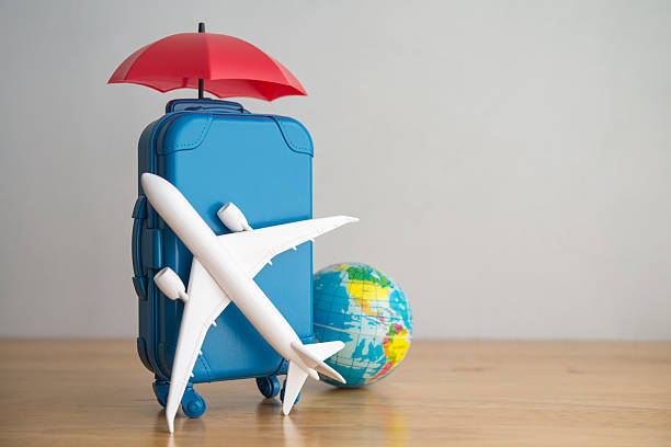 istock Umbrella, travel suitcase, airplane and globe on wooden table copy space. 2220262719