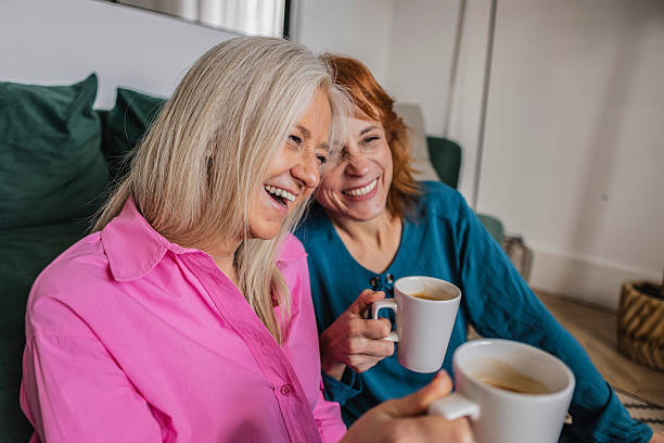 istock Two senior women laughing and drinking coffee at home 2220264743