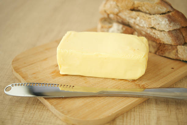 istock Butter on wooden board next to sliced bread with knife 2220266931