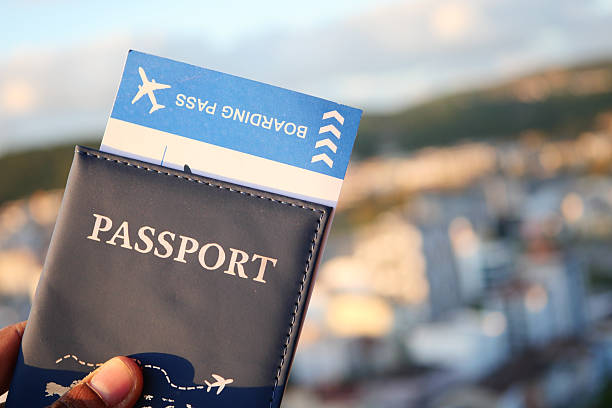 A hand holds a passport and boarding pass against a city backdrop.