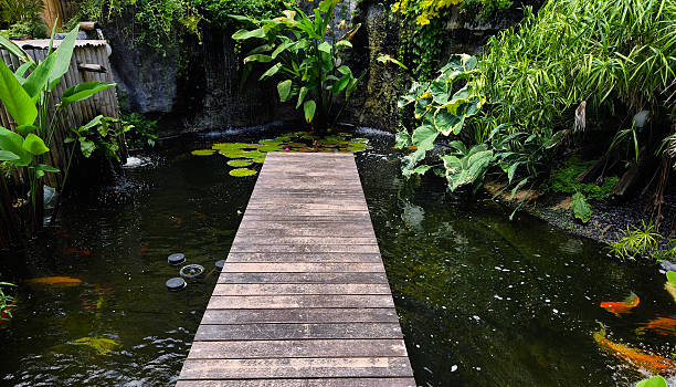 deckchair made of wooden planks as furniture for a public park or courtyard of an office building. hole for square shaped tree trunk. around ornamental grass and paving rope fence, salvia nemorosa