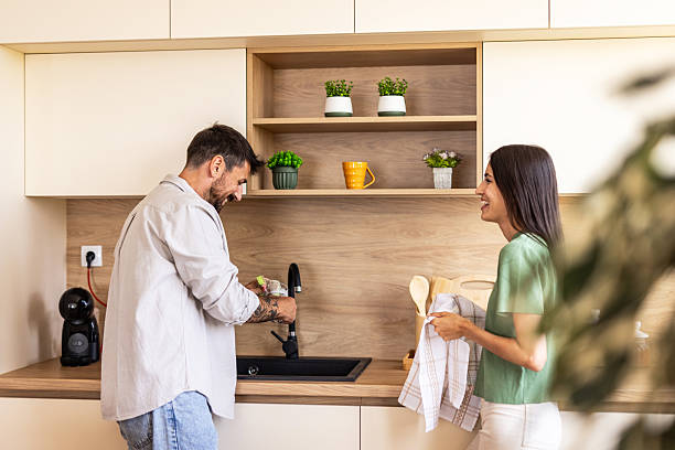 istock Couple washing dishes and having fun in modern kitchen 2220267948
