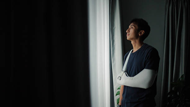 istock Man with arm cast looking out window. 2220270642