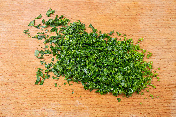 Fine chopped parsley pile on a wooden chopping board, minimal  backdrop