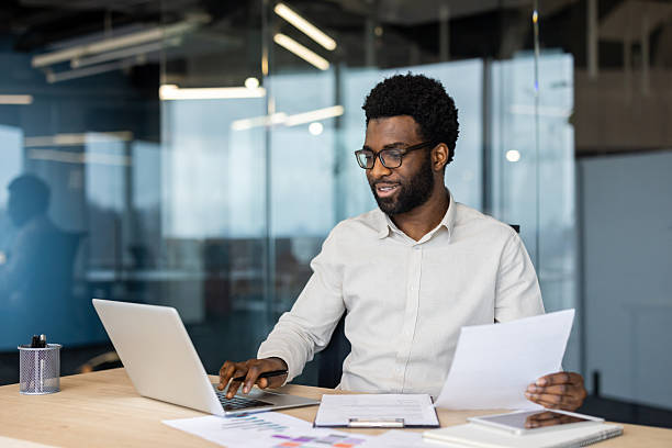istock Successful businessman financier doing paperwork inside office, man preparing reports, and working with documents and papers. Company employee accountant, holding a contract in hands smiling happily 2220277515
