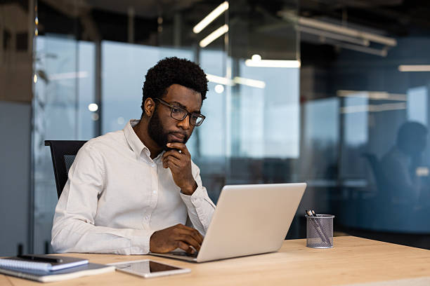 istock Serious thinking businessman at workplace inside office working with laptop. Man in shirt working concentrated, preparing electronic financial report 2220277651