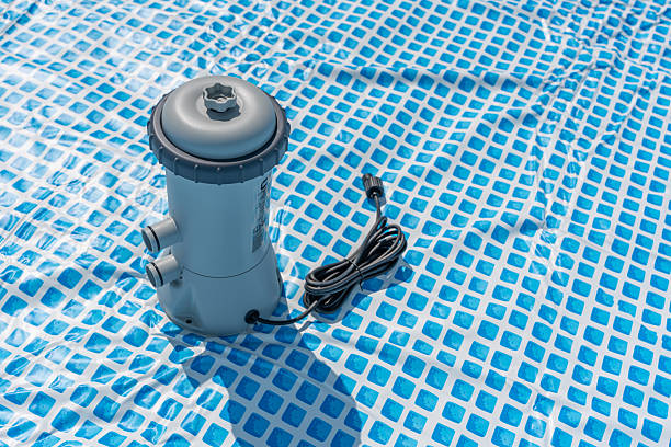 The pool pump is standing on the blue surface, the cable is wound up.