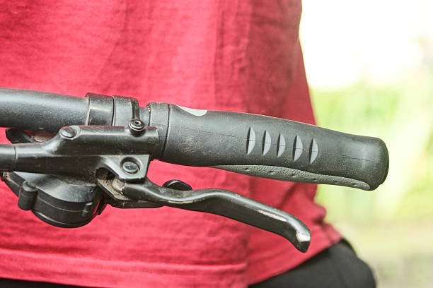 part of a black metal bicycle handlebar with a handbrake and a plastic handle in the street