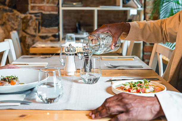istock Elegant Fine Dining Table Setting with Person Pouring Water into a Glass 2220290276