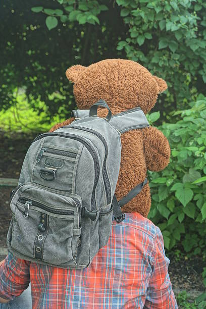 istock one man in colorful clothes holding big brown toy bear with gray backpack 2220290281