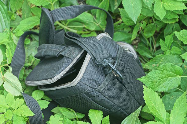 one small open black bag made of fabric lies on the green grass and ground on the street
