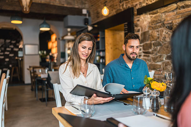 istock Stylish Young Couple Reading Menu at Rustic Stone Restaurant During Casual Dinner 2220292625