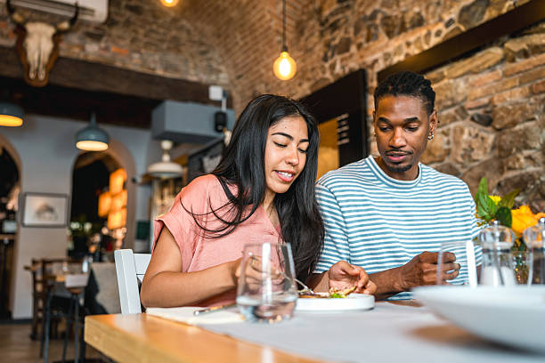 istock Diverse Young Couple Enjoying Casual Dinner In Rustic Brick-Walled Restaurant With Ambient Lighting 2220292672