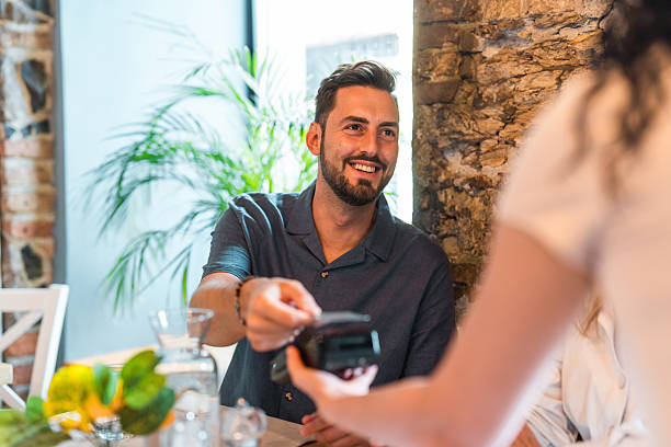 istock Hispanic Man in Blue Shirt Making Contactless Payment at Upscale Restaurant 2220292675