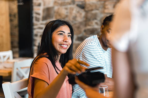 istock Young Hispanic Woman Making Contactless Payment in Elegant Fine Dining Restaurant 2220292692