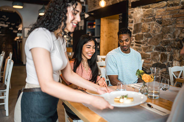 istock Young Hispanic Waitress Serving Guests in Elegant Fine Dining Restaurant with Stone Walls 2220292736