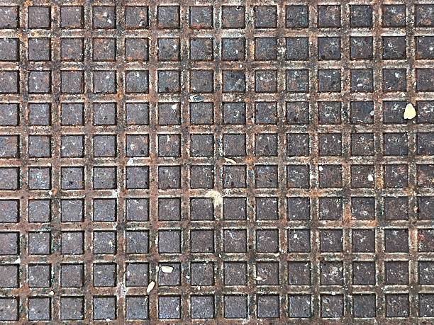 Detailed view of a metallic grid featuring rectangular textured patterns, showcasing rust and weathered aspects, symbolizing industrial design, aged materials, and urban aesthetics.