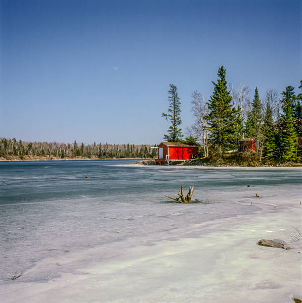 Rural home on a lake in the morning in Canada. The lake is quiet and the house reflected in the lake.
