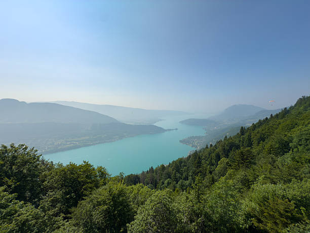 A panoramic view from Col de la Forclaz reveals the full expanse of Lake Annecy, shimmering beneath the hazy outline of distant mountains.