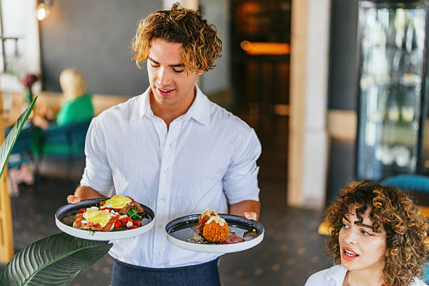 istock Waiter Serving Delicious Dishes in a Cozy Restaurant Setting 2220301271