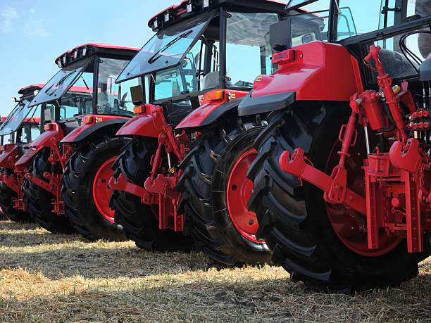 istock Rear view of several large modern red tractors standing in a field. 2220302183
