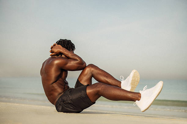 istock Man exercising on beach performing sit-ups with ocean background 2220302400