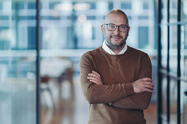 istock Smiling mid-age businessman standing confidently in a modern office space 2220303570