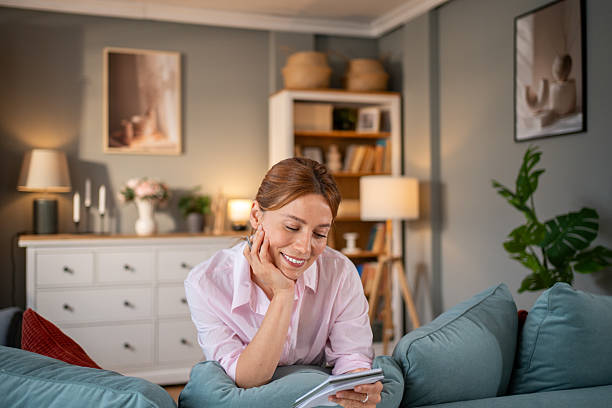 istock Smiling woman reading notes on sofa in cozy living room 2220303717