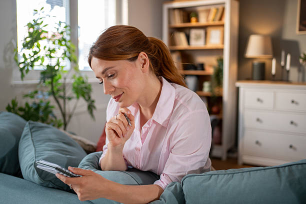 istock Woman relaxing on sofa reading notes and planning at home 2220303751