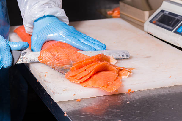 istock Fish production. Worker cuts fish with a knife into pieces for packaging 2220304029