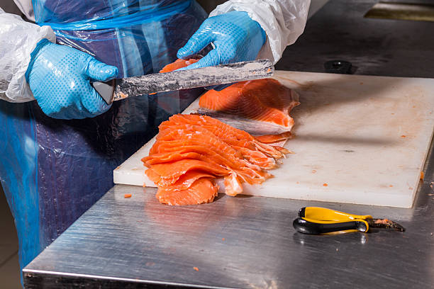 istock Fish production. Worker cuts fish with a knife into pieces for packaging 2220304052