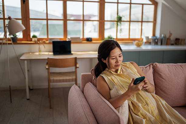 istock Pregnant woman relaxing on sofa using smartphone at home 2220304202